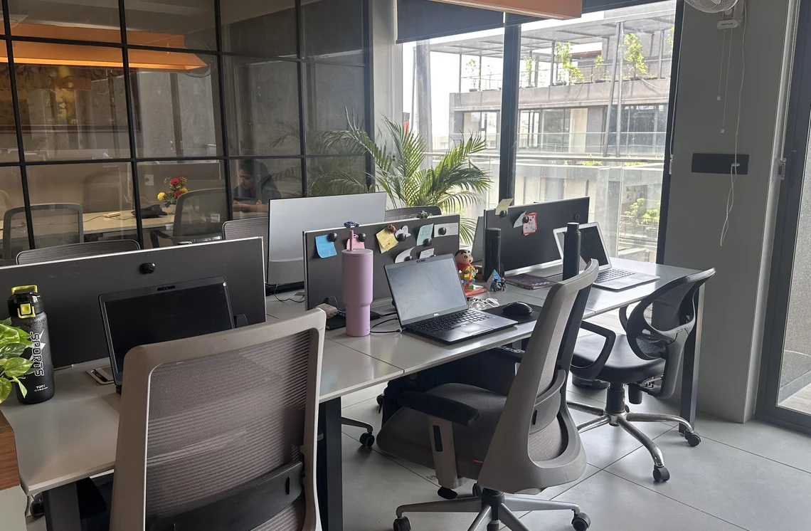 Open workspace with desks and chairs beside large windows